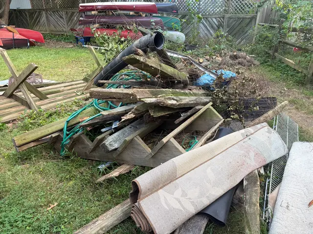 Old boards and dismantled wooden sections piled beside a canoe rack before removal.